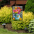 Briarwood Lane Gerber Daisy Watering Can garden flag with colorful flowers, butterflies, and checkered pattern.