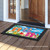 Briarwood Lane Hanging Flip Flops colorful doormat with floral design on wooden porch outside doorway.