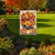 Briarwood Lane Autumn Bouquet Garden Flag with vibrant fall flowers and pumpkins on a black stand.