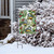Briarwood Lane Winter Chickadees garden flag with pinecones and holly on a snowy display stand.