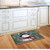 Briarwood Lane Smiling Snowman Doormat on a wooden kitchen floor with white cabinets background.