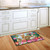 Briarwood Lane Bunny Family Doormat with colorful bunnies and flowers on wooden kitchen floor.