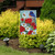 Briarwood Lane Spring Friendship Garden Flag with blue bird, red flowers, and white daisies displayed outdoors.