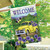 Briarwood Lane yellow pickup truck house flag with purple flowers and welcome text on garden banner.