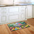 Briarwood Lane Birdbath in Bloom colorful floral doormat on wooden kitchen floor beside white cabinets.