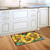 Briarwood Lane Buzzing Sunflowers doormat on wooden floor beside kitchen sink and white cabinets.