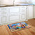 Briarwood Lane Dog Days Beach Doormat on wooden floor in front of kitchen sink area.