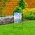 Briarwood Lane wrought iron garden flag arbor with colorful floral design and cross on metal stand.