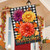 Black and white checkered house flag with colorful mums and Welcome text on a porch.