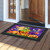 Happy Jack O Lanterns Doormat with colorful Halloween design and black border on wooden porch floor.