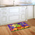 Happy Jack O Lanterns Doormat on wooden kitchen floor with white cabinets and purple background.