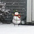 Smiling Snowman Metal Art in snowy yard with hat, red scarf, and green buttons on stand.