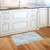 Textured Blue Doormat on wooden floor in front of white kitchen sink and cabinets.