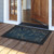 Organic Flow Doormat, blue and gold leaf design on a wooden porch outside an open doorway.