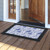 Blue and white floral doormat on a wooden porch with black border.