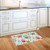 Spring Floral Doormat with pink flowers and green leaves on light blue background in kitchen.