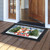 Snow Family Doormat with Christmas snowmen and trees design on wooden porch outside open door.