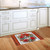 Holiday Poinsettia Wreath Doormat on wooden floor in front of white kitchen cabinets and sink.