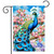 Vibrant peacock on Fancy Peacock Garden Flag with pink flowers and blue sky background displayed outdoors.