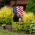 Saluting Soldier Garden Flag with American flag and soldier saluting, outdoors in a garden setting.