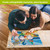 Couple working on Briarwood Lane Summer Gnomes 1000-piece jigsaw puzzle on wooden floor together.