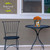 Briarwood Lane Fall Gnomes Small Planter with orange flowers on a black metal table and chair.