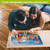 Couple assembling Briarwood Lane Dog Days Beach 1000 Piece Jigsaw Puzzle on wooden floor together.
