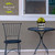Briarwood Lane Checkerboard Small Planter with yellow flowers on a small black metal table outdoors.