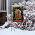 Holiday Birdhouse Garden Flag with cardinals, snow-covered bush, and welcome sign on a metal stand.