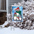 Penguin Family Garden Flag with snow scene and penguins wearing hats and scarves on display outdoors.