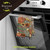 Bountiful Bushel Cotton Hand Towel with pumpkin and sunflower design hanging on oven handle.