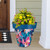 Large Abstract Floral planter with blue rim and colorful flowers on a front porch setting.