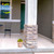 Small colorful flowers planter on a porch next to a stone pillar and green door.