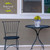 Small blue and white floral planter on a black metal table beside a matching chair outdoors.