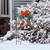 Winter Watering Can Garden Flag with cardinals, poinsettias on snowy bush outside house with gray siding.