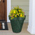 Tropical Leaves Large Planter, green leaf-patterned pot with yellow flowers and pink blooms on a porch.