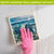 Seaside Escape Summer Swedish Dishcloth, pink glove holding colorful coastal design dish towel against surface.