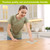 Woman wiping wooden table with Flowing Leaves Swedish Dishcloth, green and white kitchen background.
