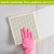 Flowing Leaves Swedish Dishcloth, beige with leaf pattern, held by pink gloved hand on surface.