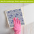 Blue and white floral Swedish dishcloth with pink gloved hand wiping surface clean effectively.