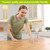 Woman using Colorful Flowers Swedish Dishcloth in a kitchen, wiping wooden table surface clean.