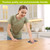 Woman using Happy Blooms Swedish Dishcloth on a wooden table with colorful floral design.