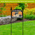 Checkered pumpkins acrylic art sign on a black metal stand in a garden setting outdoors.