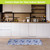 Blue and white oversized floral comfort mat on a wooden floor in a modern kitchen setting.