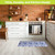 Blue and white oversized floral comfort mat in a kitchen setting on a light wood floor.