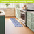 Blue and white oversized floral comfort mat on kitchen floor beside mint green and cream cabinets.