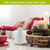 Small white tree magnetic paper decor on table beside red cup and lit white candles.