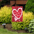 Red garden flag with white hearts and "Happy Valentine's Day" text on black metal stand outdoors.