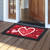 Red Heart Toss doormat with white and pink hearts and Happy Valentine's Day text on wooden porch.
