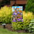 Spring Bunny Trio Garden Flag with purple flowers, butterflies, and brown bunnies on a garden stand.